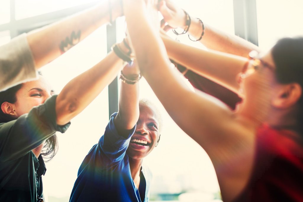 verschiedene Erwachsene unterschiedlicher Hautfarbe klatschen sich ab